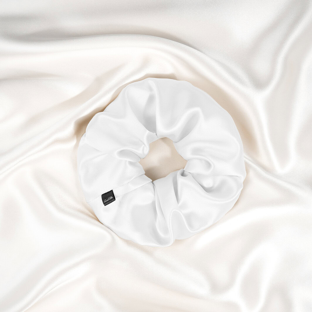 Luxuriöser Seiden-Haarband in edlem Weiß auf seidigem Stoffhintergrund.