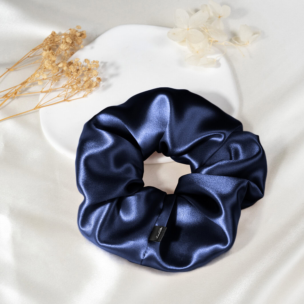 Wechselndes Nähe: Seidiger, dunkler Haarband aus Seide auf weißem Stoff mit Trockenblumen. Perfekt für luxuriöse Schönheit und Komfort.