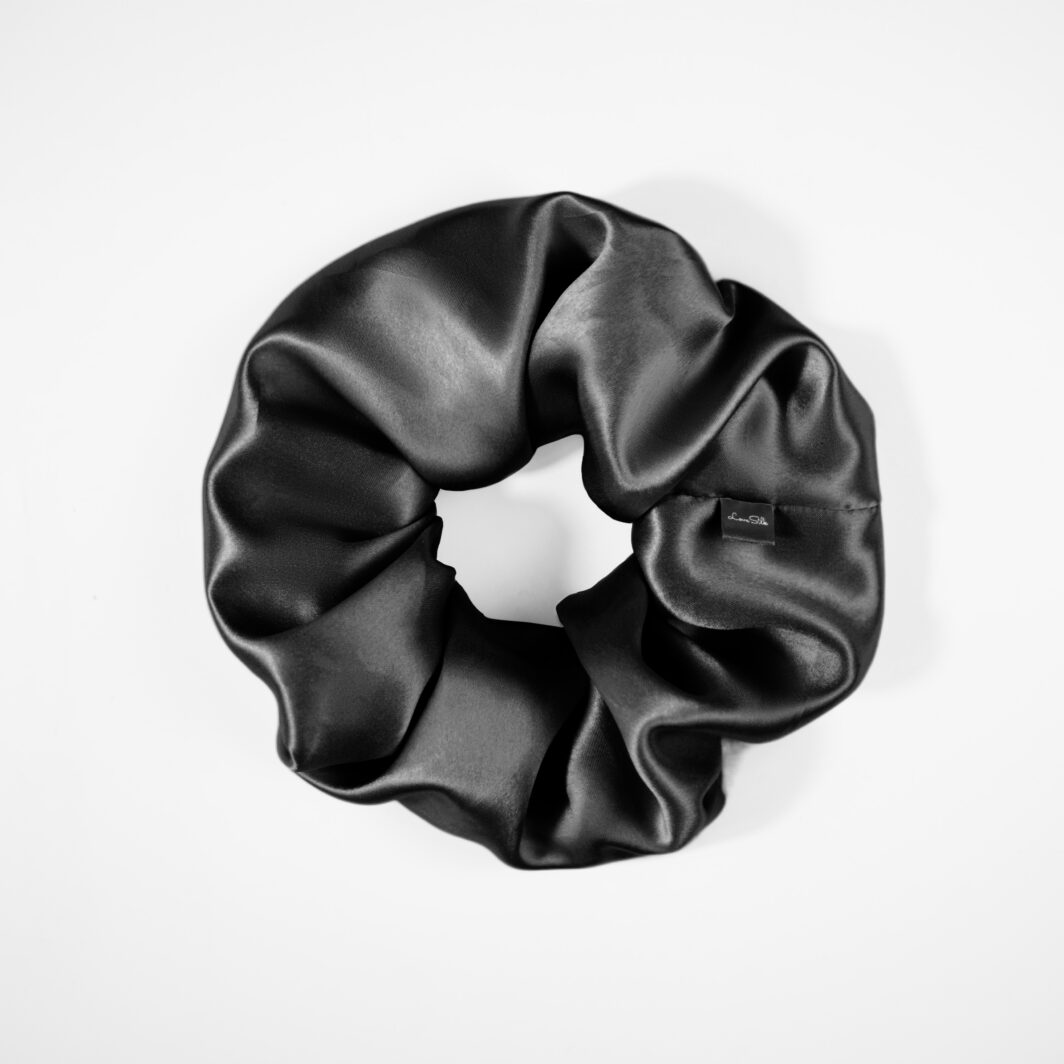 Luxuriöser schwarzer Seidenschal in elegantem Ruchmuster, sanftes Satin-Finish.