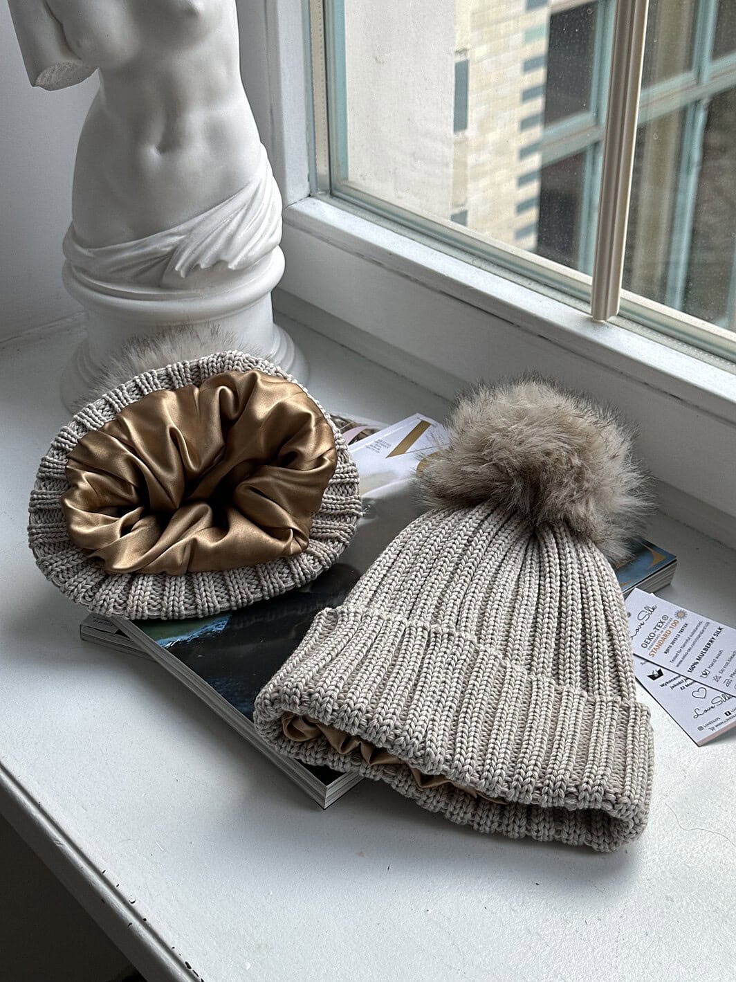 Luxuswachsmütze und Seidenschal aus Seide auf Fensterbank.