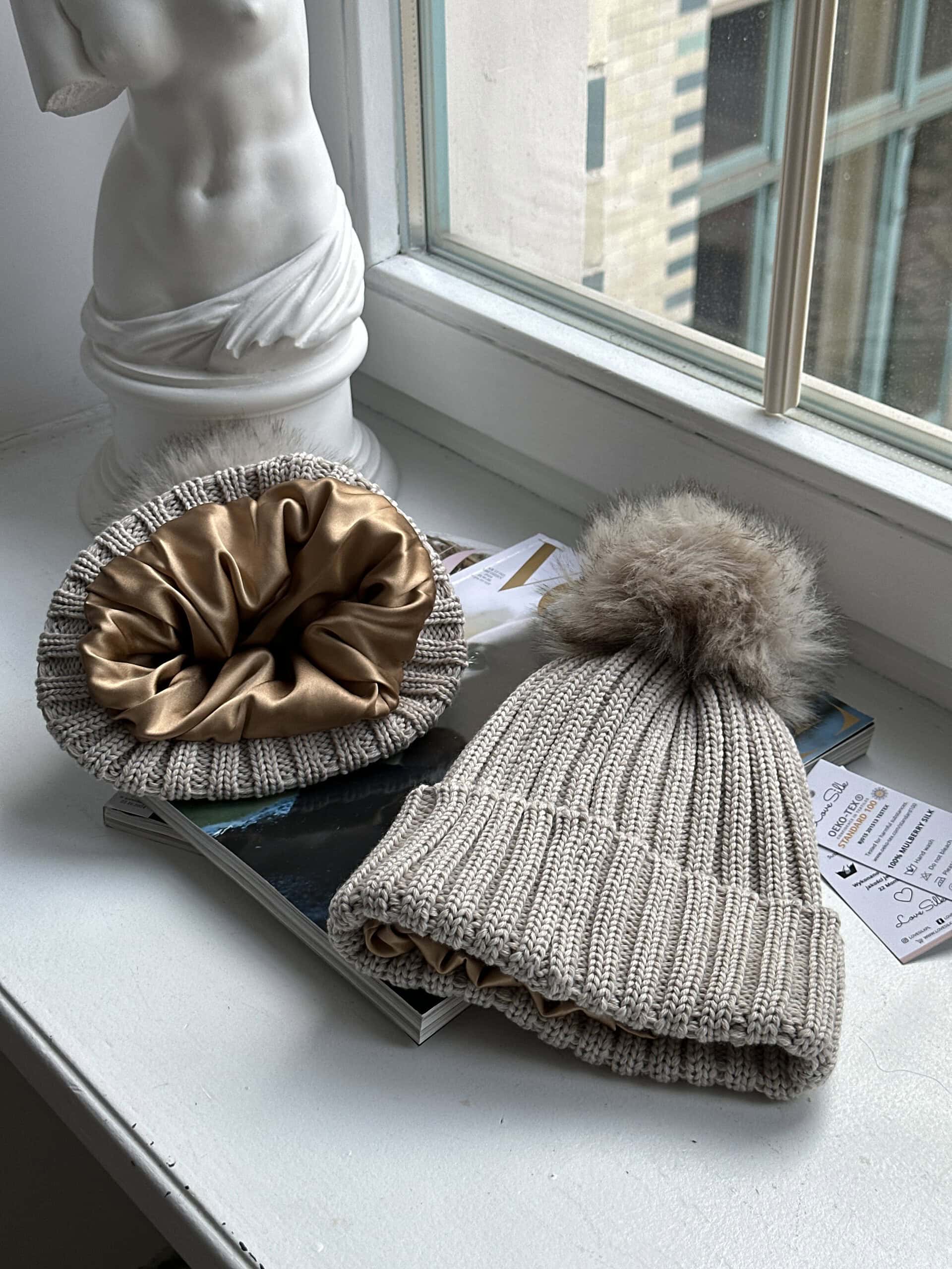 Luxuswachsmütze und Seidenschal aus Seide auf Fensterbank.