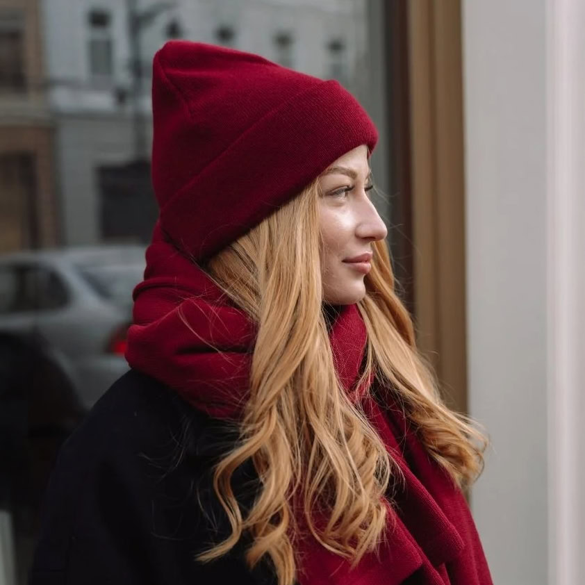 Naturrote Frau in roter Mütze und Schal, draußen in der Stadt, elegant und stilvoll gekleidet.